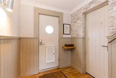 a hallway with a white door and a stone wall at The Harbour Guest House in Irvine