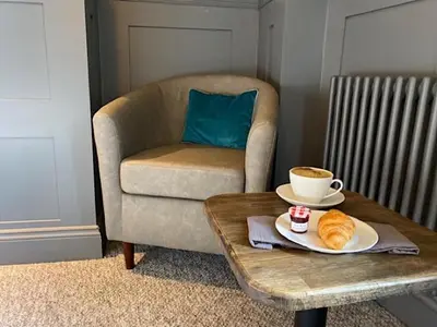 a coffee table with a cup of coffee and a plate of bread at Irvine Guest House in Irvine