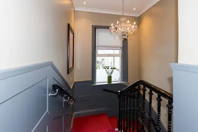 a staircase with a chandelier and a red rug at Irvine Guest House in Irvine