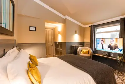 a hotel room with a bed and a tv at Irvine Guest House in Irvine