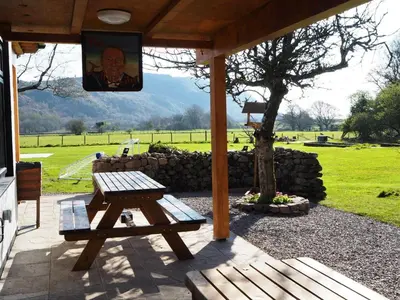 a wooden picnic table under a pavilion with a tree at Bower House Inn in Eskdale