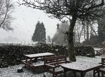 a snow covered park with benches and a christmas tree at Bower House Inn in Eskdale