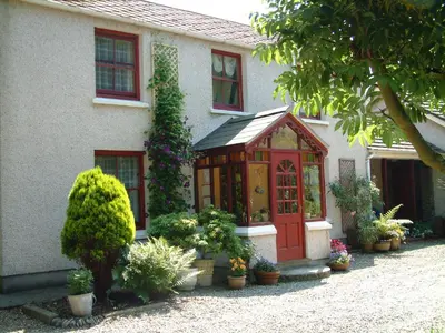 a house with a red door and some plants at Ballacowell Cottage in Sulby