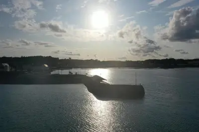 a boat in the water with the sun in the sky at Cladach in Garlieston