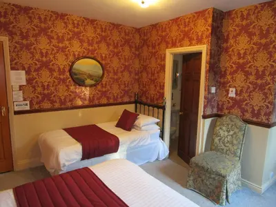 a hotel room with two beds and a chair at Brookfield B&B Guest House in Keswick