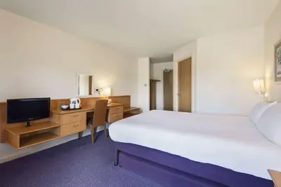 a hotel room with a bed and a desk with a television at Days Inn Lockerbie - Annandale Water in Johnstonebridge