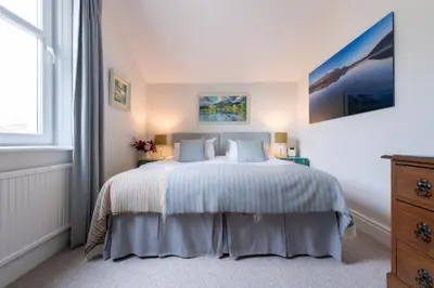 a bedroom with a bed with white sheets and pillows at The Mount self-catering in Portinscale