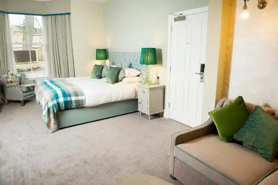 a bedroom with a bed and a couch and a chair at Crown Hotel Wetheral in Carlisle