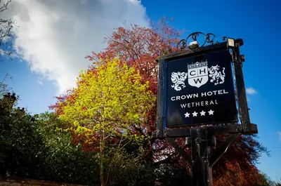 a sign for a green hotel in front of a tree at Crown Hotel Wetheral in Carlisle