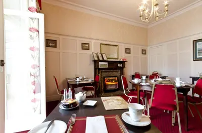 a dining room with tables and chairs and a fireplace at Inverlea Guest House in Ayr