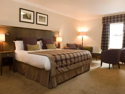 a hotel room with a large bed and a desk at The Loans Inn in Troon