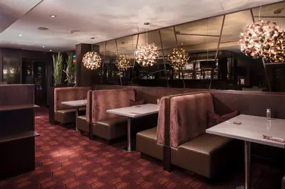 a restaurant with tables and chairs and chandeliers at Carlton Hotel in Prestwick