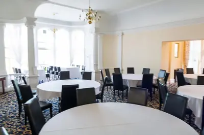 a room with white tables and chairs and a room with tables at Adamton Country House Hotel in Prestwick