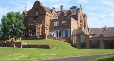 a large brick house with a green lawn in front of it at Adamton Country House Hotel in Prestwick