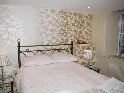 a bedroom with a large bed with floral wallpaper at Chaucers Nook in Keswick