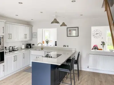 a kitchen with white cabinets and a blue island at Causey View in Keswick