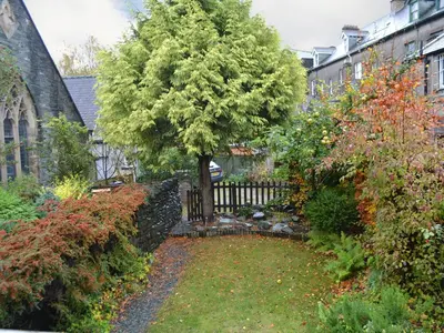 a garden with a wooden fence and a tree at Beny Cot in Keswick