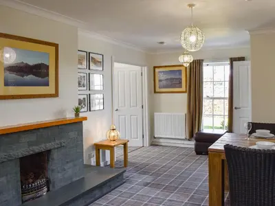 a living room with a fireplace and a table at Oak Apple House in Keswick