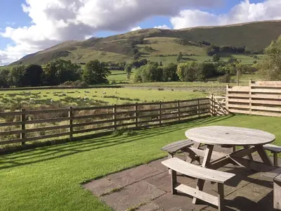 a picnic table with a view of a field at The Garth in Mungrisdale