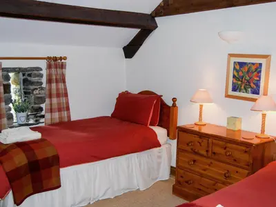 a bedroom with a red bed and a wooden dresser at The Garth in Mungrisdale