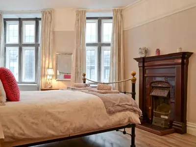 a bedroom with a bed with a fireplace and windows at Bag End in Keswick