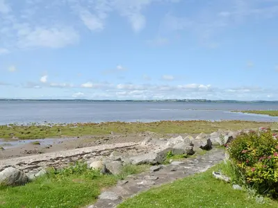 a beach with rocks and water in the background at Shore Cottage in Carsluith