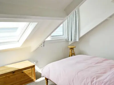 a bedroom with a bed and a window at Shore Cottage in Carsluith