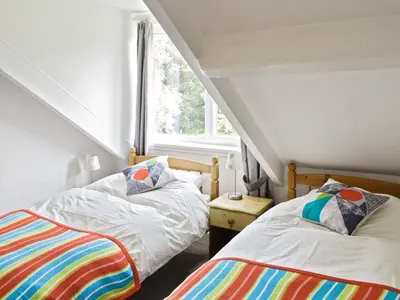 two beds in a room with a window at Shore Cottage in Carsluith