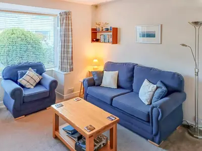 a living room with two blue couches and a table at Heatherside in Portinscale