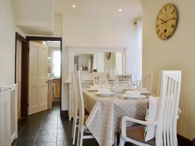 a dining room with a table with chairs and a clock at Oak Lea in Keswick
