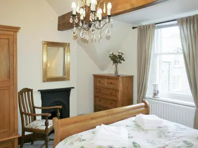a bedroom with a bed and a chair and a chandelier at Oak Lea in Keswick