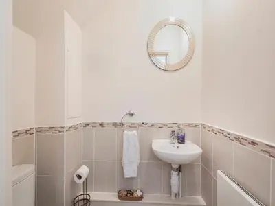 a white bathroom with a sink and a mirror at Harbour Retreat in Garlieston