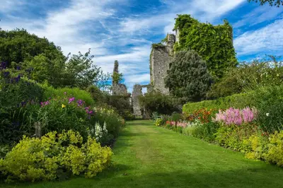a garden with flowers and a castle in the background at Thornbank House in Stranraer