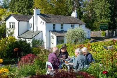 a group of people sitting around a table in a garden at The Mount B&B in Keswick