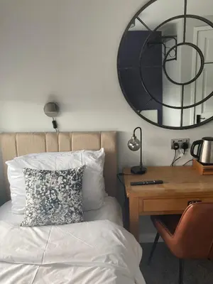 a bedroom with a bed and a desk and a mirror at Abbey Court Guest House in Carlisle