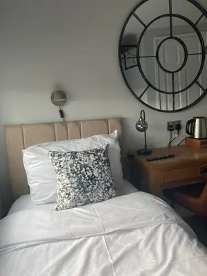 a bed with a pillow and a desk with a mirror at Abbey Court Guest House in Carlisle
