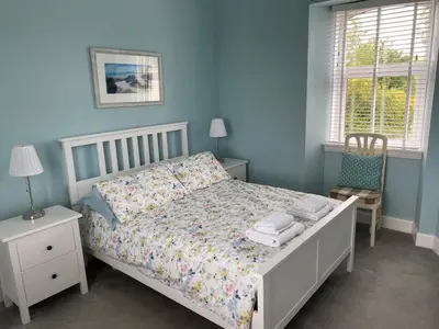 a blue bedroom with a bed and a chair at Old Station House - Kilfillan Cottage in Garlieston