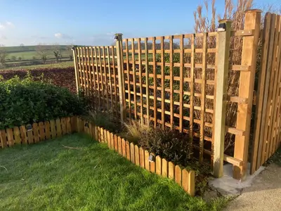 a wooden fence in a yard with grass at Old Station House - Kilfillan Cottage in Garlieston