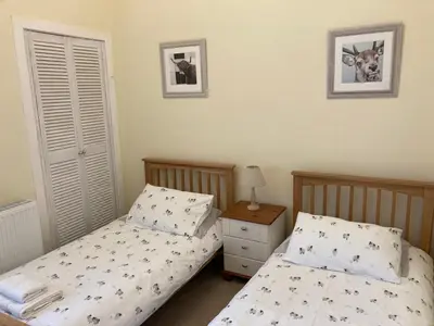 a bedroom with two beds and a nightstand with at Old Station House - Kilfillan Cottage in Garlieston