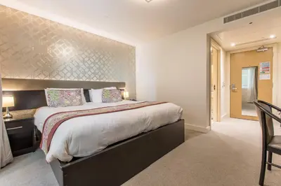 a bedroom with a large bed and a table and chairs at Mannin Hotel in Douglas