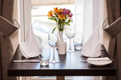 a table with glasses and a vase of flowers on it at Mannin Hotel in Douglas