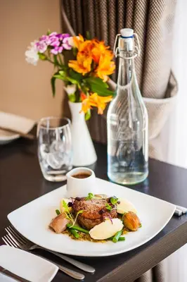 a plate of food on a table with a vase of flowers at Mannin Hotel in Douglas