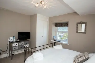a bedroom with a bed and a tv and a window at Baie Mooar House, Boutique B&B in Ramsey