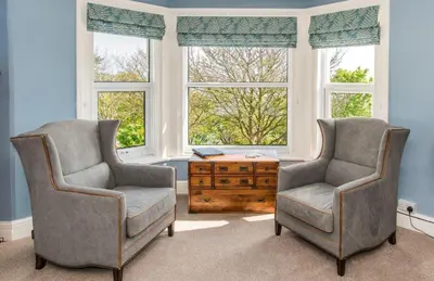 two chairs and a table in a room with windows at Baie Mooar House, Boutique B&B in Ramsey