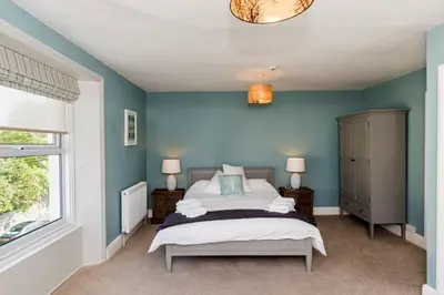 a bedroom with a bed with blue walls and a window at Baie Mooar House, Boutique B&B in Ramsey