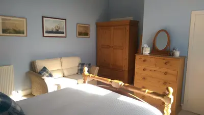 a bedroom with a bed and a dresser and a mirror at Lochinver Guesthouse in Ayr