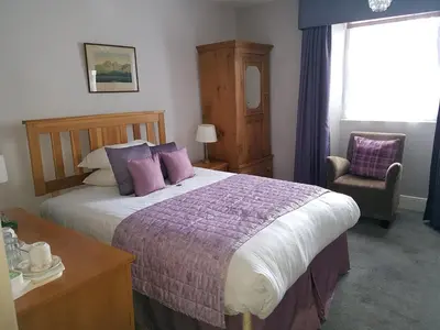 a bedroom with a bed and a chair and a window at The Old Dungeon Ghyll Hotel in Great Langdale