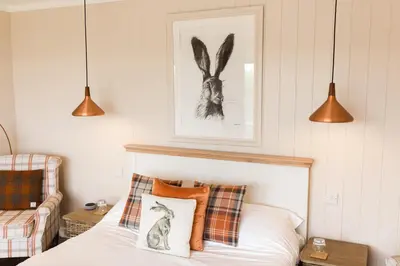 a bedroom with a bed with pillows and a picture of a rabbit at Sea View Snugs at Laggan in Gatehouse of Fleet