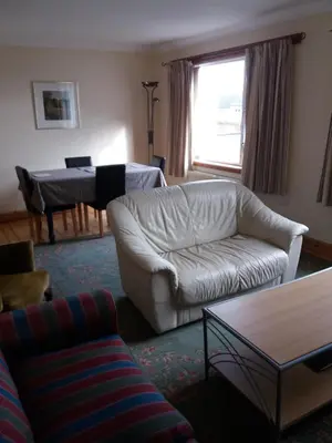 a living room with a white couch and a piano at House for Groups & Contractors Kilmarnock in Kilmarnock