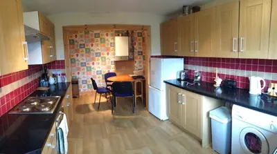a kitchen with a table and a white refrigerator at House for Groups & Contractors Kilmarnock in Kilmarnock